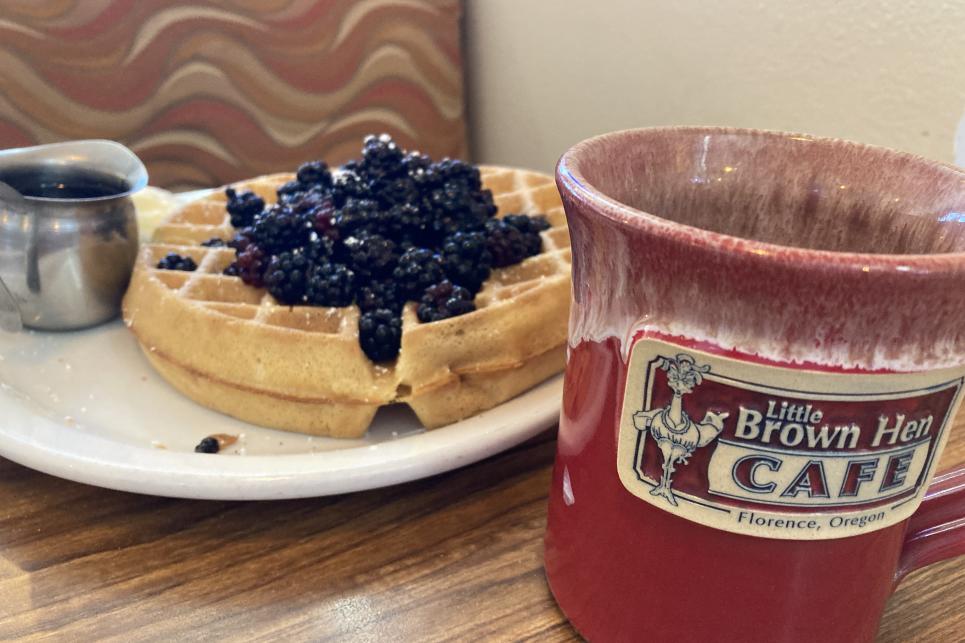A blackberry waffle with a cup of coffee.