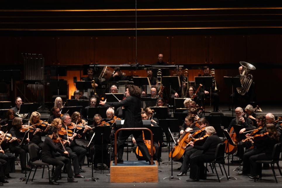 The conductor leads the Eugene Symphony on stage.