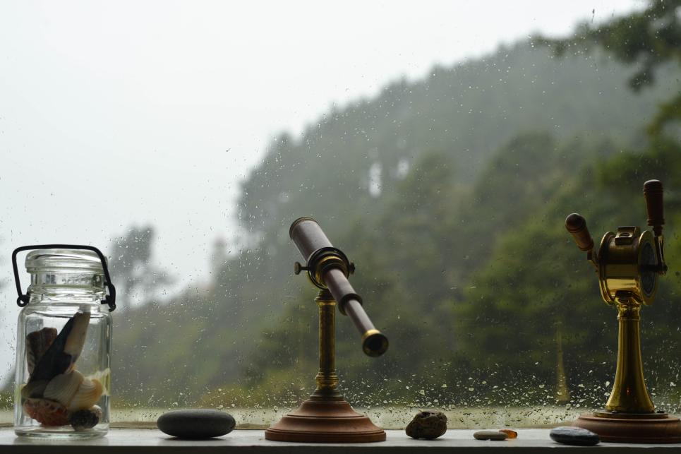 A rain splashed window with items on the windowsill.