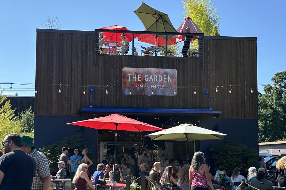 Bright red and yellow umbrellas over outside tables on the garden level and the roof top deck of The Garden food hub.