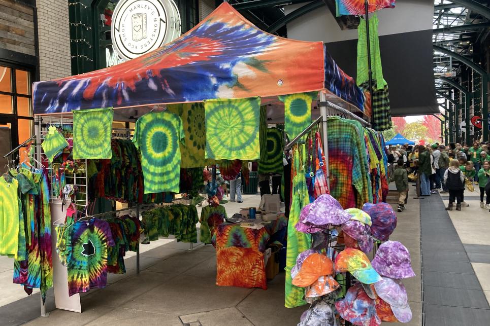 A booth with tie-dye displayed on shirts, bandanas and hats.