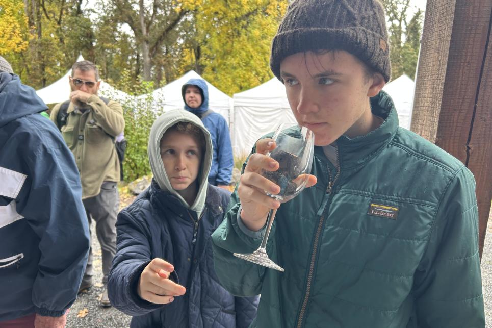 Two kids smell truffles in a glass.