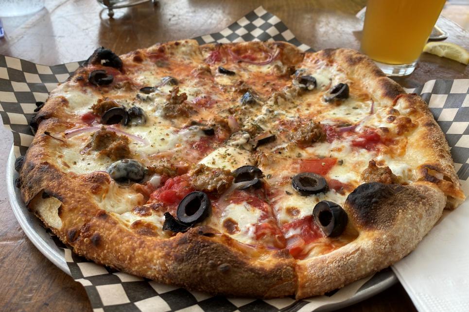 A woodfired pizza on a black and white checked paper.