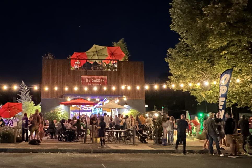 Garden on Friendly is lit up with lights and crowded with people around its outdoor patio.