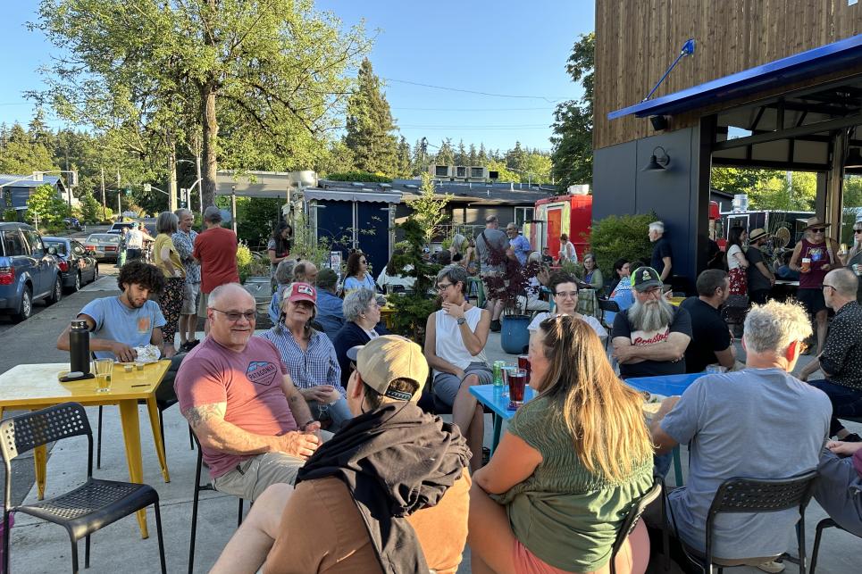People sit at tables on the patio outside the Garden on Friendly food truck pod.