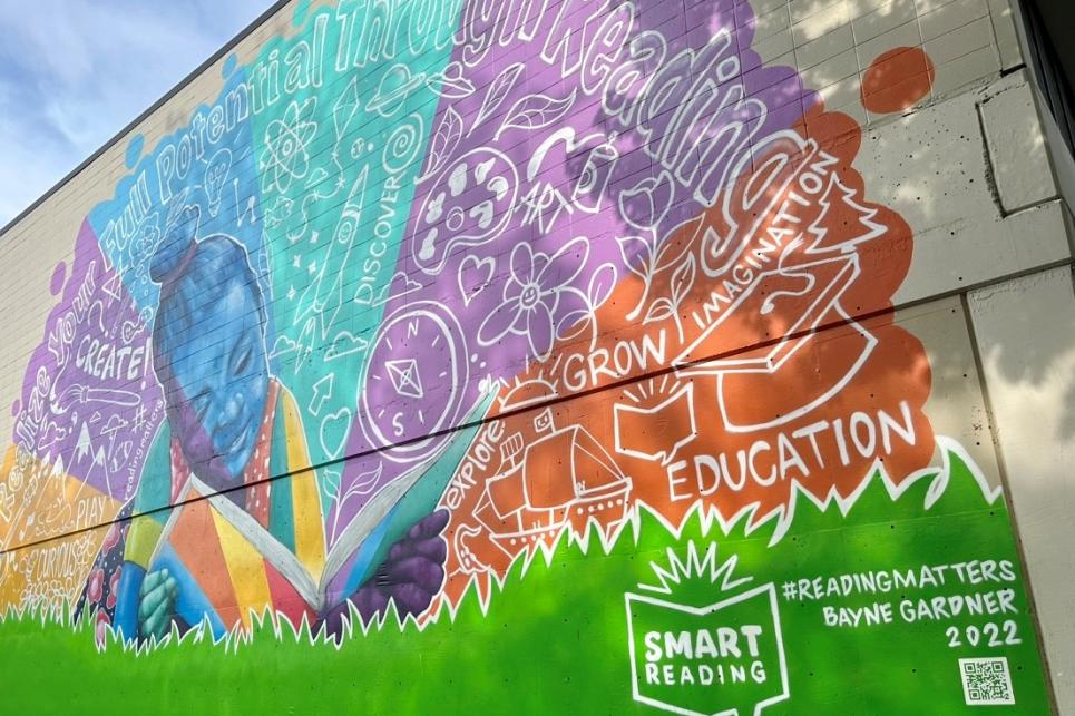 A brightly colored mural with a child reading and white lettering of positive words behind them including "grow", "education" and "reading". The Smart Reading logo is at the bottom of the mural.