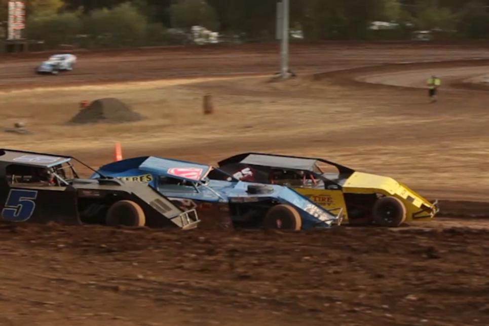 Three racecars grip the inside dirt track at the Cottage Grove Speedway.