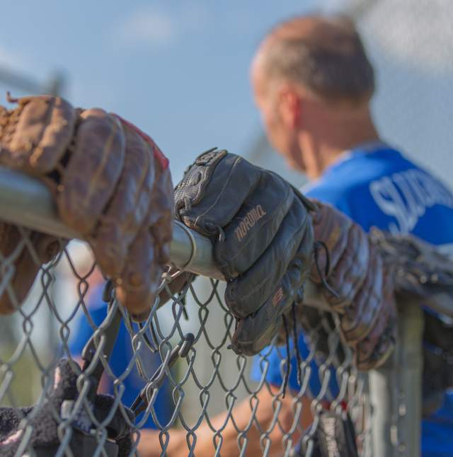 Softball gloves on a fence