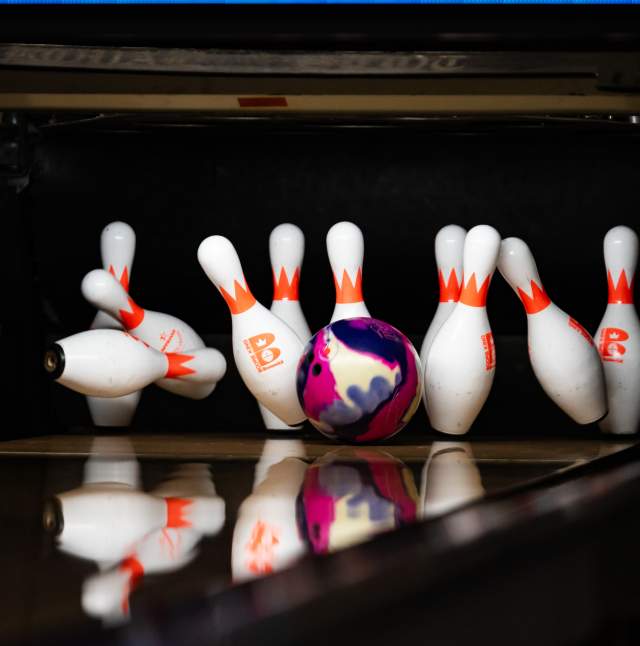 A colorful bowling ball striking pins at Royal Scot Bowling Center.