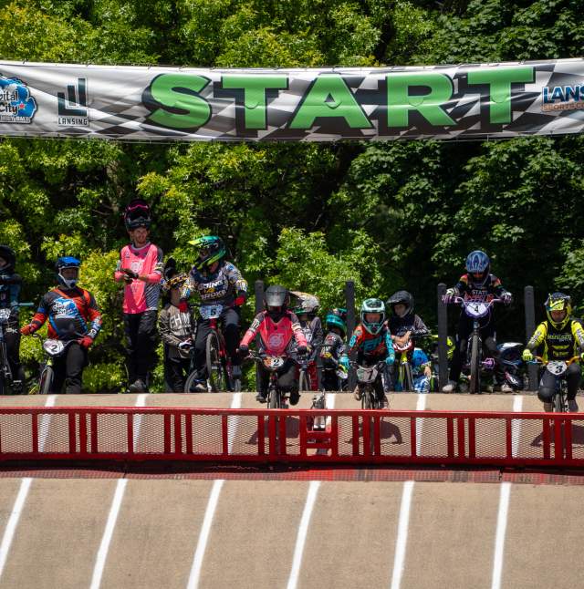 A group of BMX athletes lining up at the start, preparing for their run during the BMX State Race.