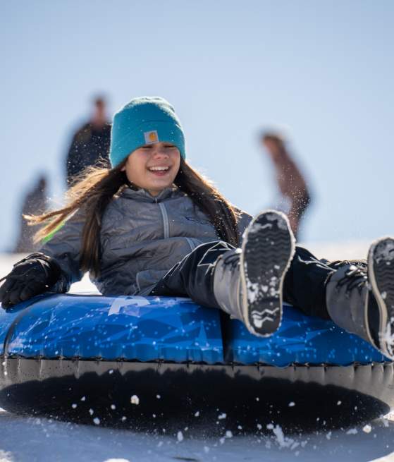 girl on sled going down snow hill