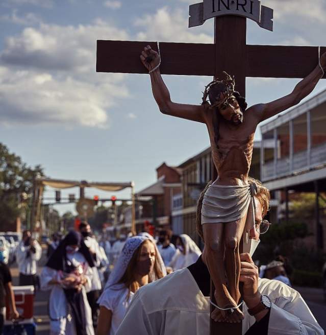 man walking with large crucifix