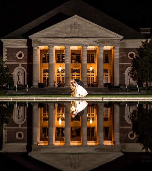 Newly weds pose outside the hall of springs at night