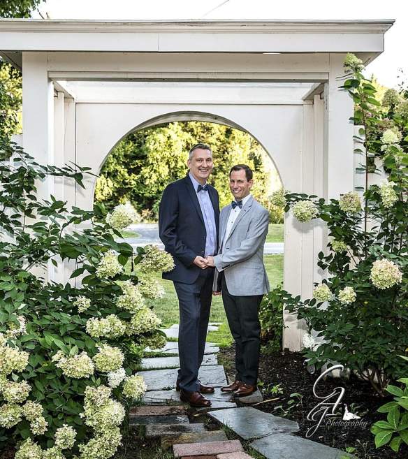 groom posing under arch