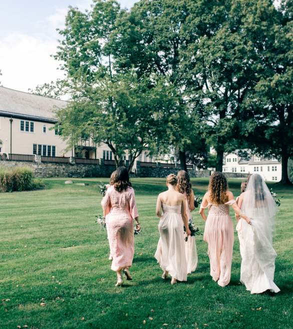 Bride and bridal party walking up back lawn toward the building