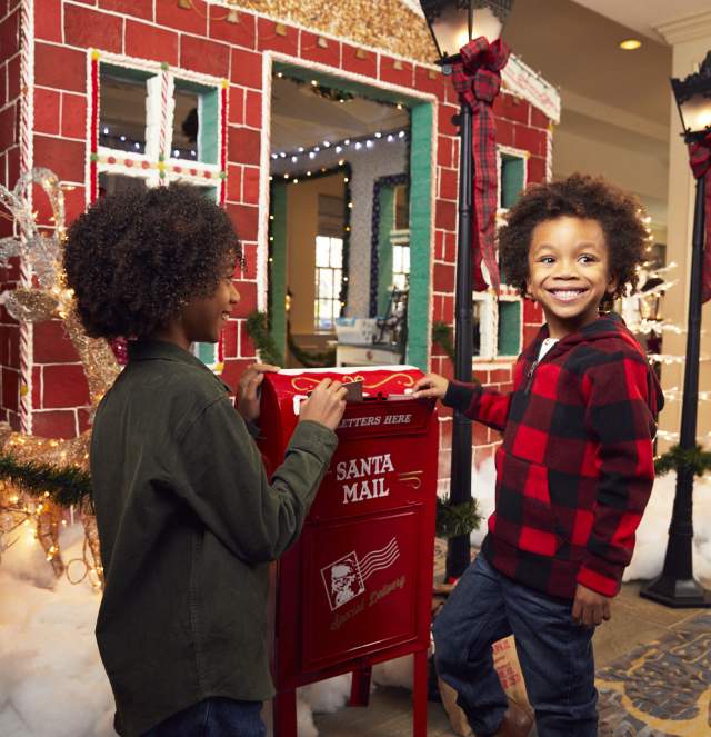 Children dropping letters to Santa Clause in holiday mailbox