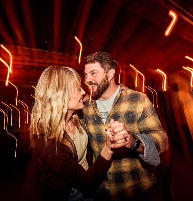 Two people dancing at night, with many lots around them.