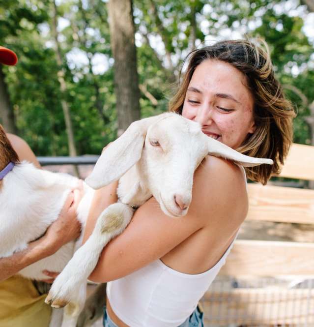 Two people holding goats.