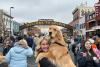 A women holding an adult golden retriever in her arms with the historic welcome to Golden arch in the background