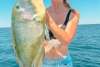 A woman in a boat holding a freshly caught Bluebone fish, in the waters off Port Hedland