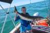 A woman in a boat holding a freshly caught cobia fish, in the waters off Port Hedland