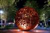 large rosette-patterned sphere in a park at night