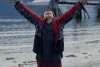 Boy celebrating the sunshine arms raised, cruise ship docked in backdrop