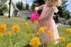 little girl in pink dress watering yellow flowers