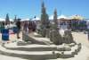 People standing around a sandcastle at Texas SandFest, showcasing impressive sand art and sculptures