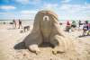 Sand sculpture of a women wiht a hole in the middle of ther head showing a smaller version of her.