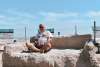 Large couch made of sand with a person sitting on top.