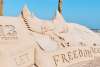 Sand sculpture that says "let freedom reign" with an eagle behind it.