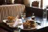 Plates of burgers and fries with a glass of wine on a table