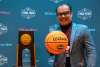 Man holding basketball by NCAA trophy
