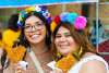 Two girls holding chicken on a stick wearing flower crows at Fiesta San Antonio.