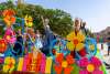 Women dressed in gowns and crowns on a colorful Fiesta float in front of the Alamo.