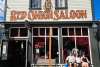 A while false front two story building trimmed in green with "Red Onion Saloon" written in big red letters under two long narrow windows on the second story