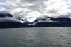 Sunrise coming up over mountain on the Talya Inlet with dramatic low clouds, while in transit to Davidson Glacier.