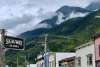 Title: Where the Mountains Meet Main Street Nestled beneath mist-covered mountains, downtown Skagway captures the striking contrast between human history and Alaska’s rugged wilderness. The bustling street, colorful Gold Rush-era storefronts, and gathering visitors reflect the town’s enduring energy, while the towering forested slopes and drifting clouds reveal the powerful landscape that continues to shape it.