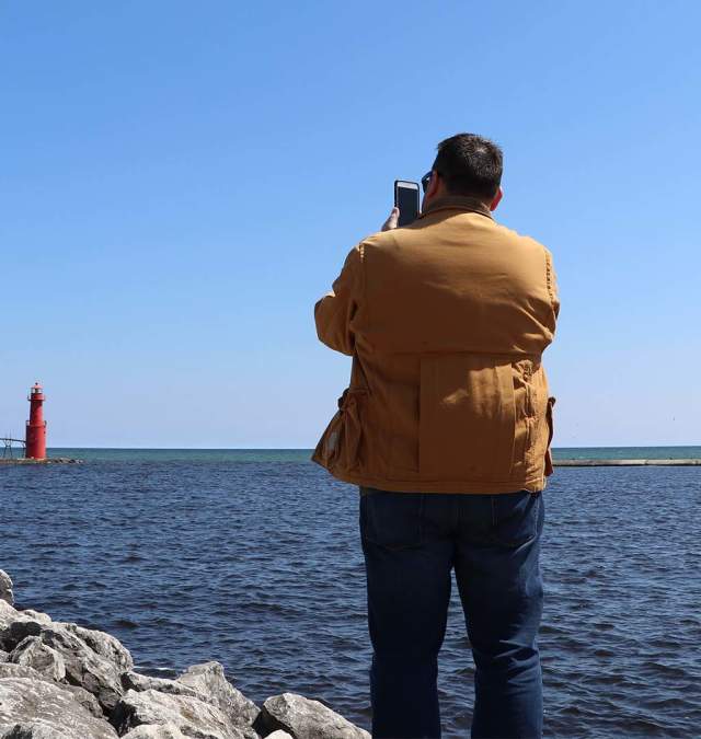 Man takes photo of lighthouse in Algoma on the shore of Lake Michigan