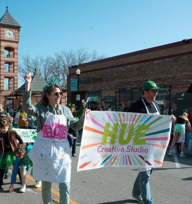 The team from Hue Creative waves to spectators at the Downtown Overland Park St. Patrick's Day Parade.