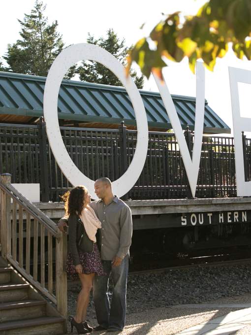 A couple standing in front of a sign that says "LOVE"