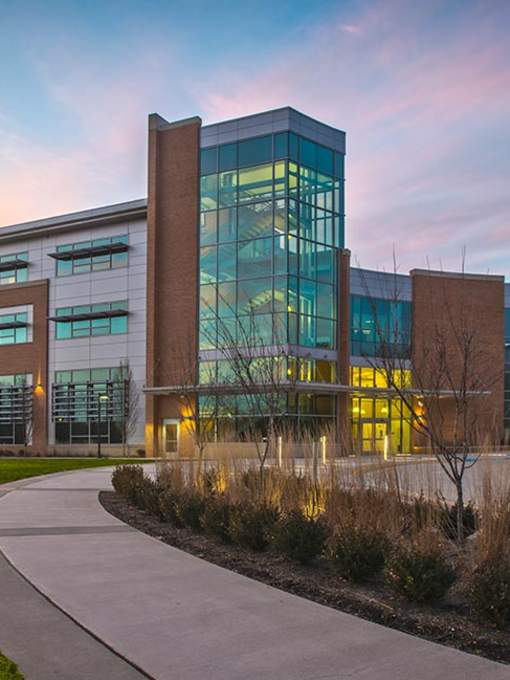 a brick building with many windows at sunset with a walking area in front of the building