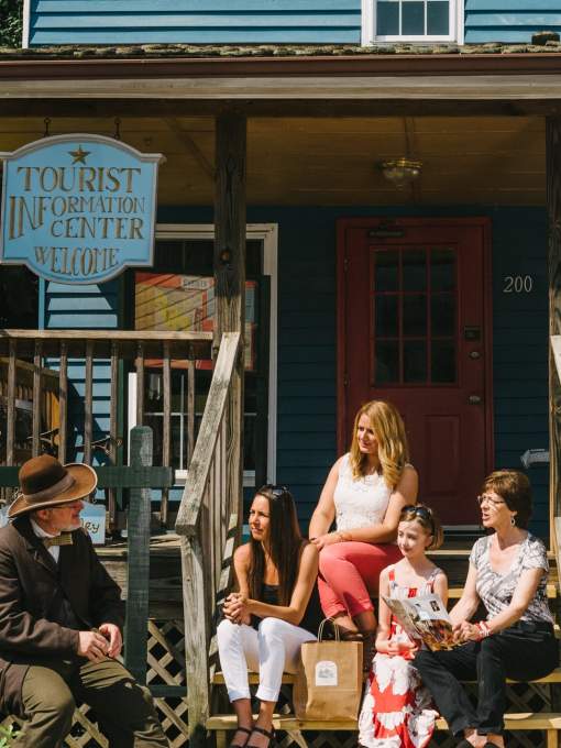 A history volunteer sitting with a group of women in front of the tourist information center