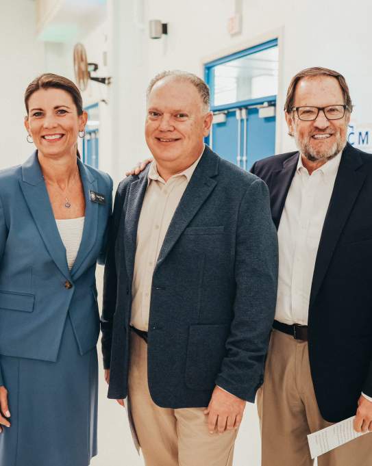 Three people in professional attire posing and smiling at the Port Aransas Summit 2025.