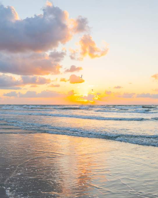 A bright, golden sunrise over the ocean waves on a beach in Port Aransas.