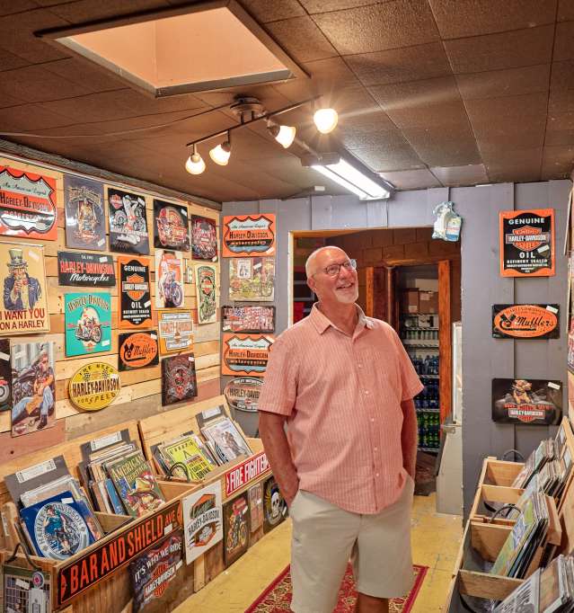 A person browsing in an antique store, looking at a wall of posters and signs.