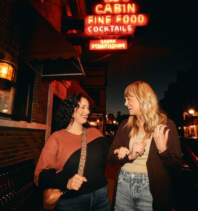 Two people on Main Street, standing in front of a neon sign.