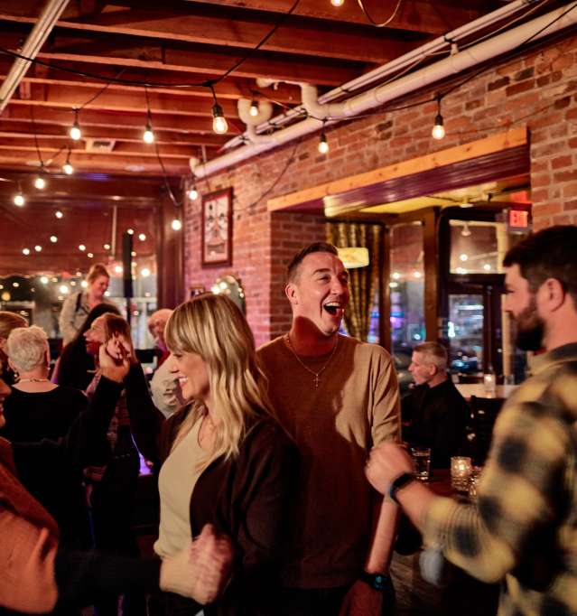 People in a busy bar with a brick wall behind them.