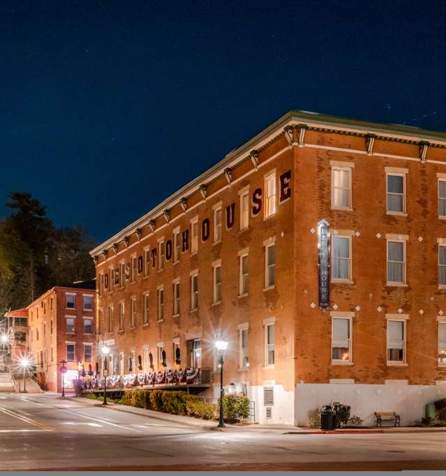 An image of the historic DeSoto House Hotel, with street lights lit, set at night.